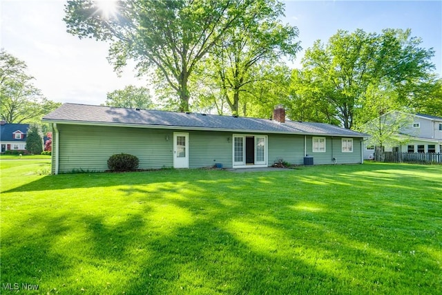 back of property featuring a lawn, a chimney, and central AC