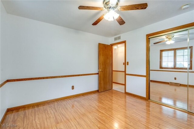 unfurnished bedroom featuring wood finished floors, a closet, baseboards, and a ceiling fan