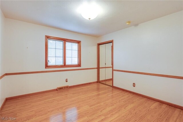 unfurnished room featuring light wood-type flooring, baseboards, and a smoke detector