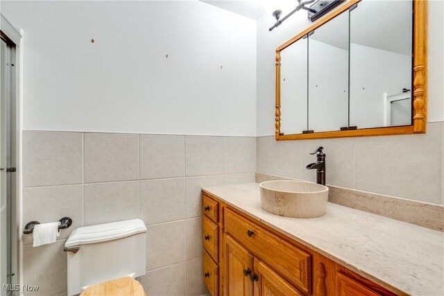 bathroom with tile walls, vanity, and toilet