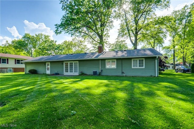rear view of house featuring a yard, cooling unit, and a chimney