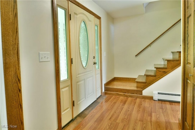 entrance foyer featuring a baseboard radiator, stairs, and wood finished floors
