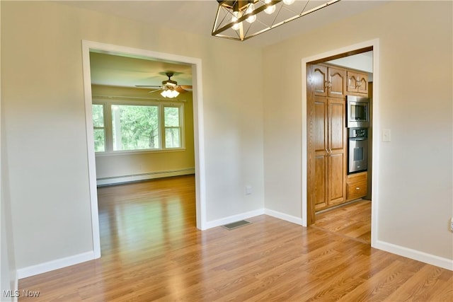 unfurnished dining area featuring baseboard heating, light wood-type flooring, and baseboards