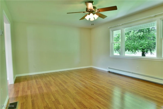 spare room featuring a baseboard heating unit, wood finished floors, ceiling fan, and baseboards