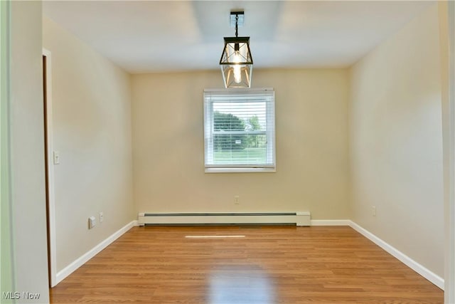 unfurnished room with a baseboard radiator, light wood-style floors, and baseboards