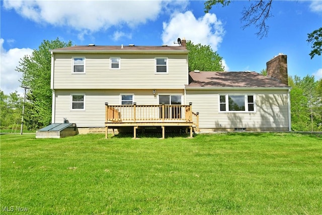 rear view of property with a chimney, a wooden deck, and a lawn