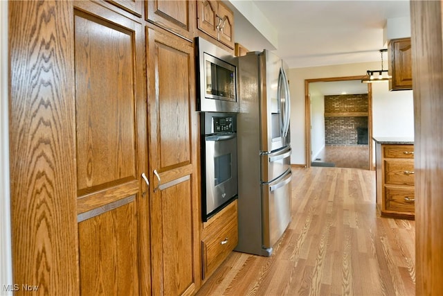 kitchen featuring stainless steel appliances, brown cabinetry, and light wood finished floors