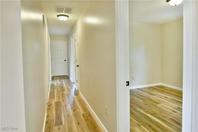 corridor featuring light wood-type flooring and baseboards