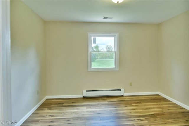 unfurnished room with baseboard heating, wood finished floors, and baseboards