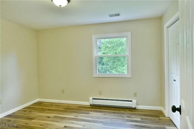 spare room featuring a baseboard radiator, wood finished floors, and baseboards