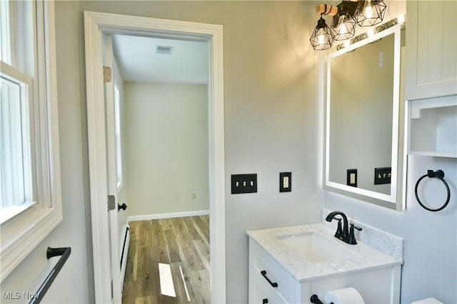 bathroom featuring a baseboard heating unit, wood finished floors, and vanity