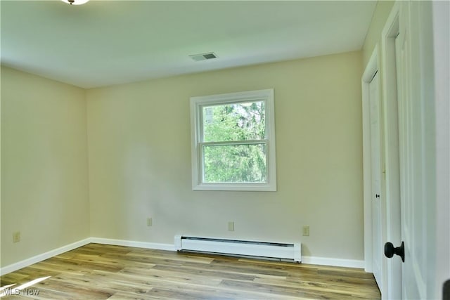 empty room with a baseboard heating unit, baseboards, and wood finished floors