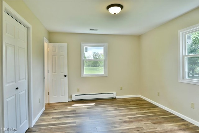 unfurnished bedroom with a baseboard radiator, wood finished floors, and baseboards