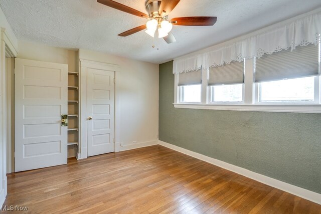 unfurnished bedroom with light wood finished floors, baseboards, a closet, a textured ceiling, and a ceiling fan