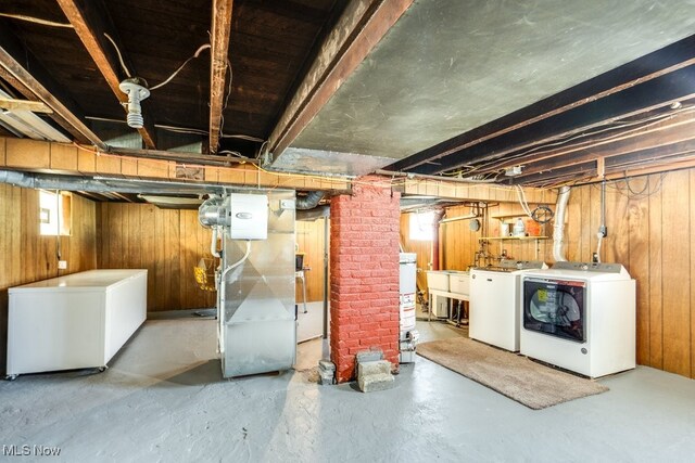 below grade area featuring washer and clothes dryer, wooden walls, fridge, heating unit, and gas water heater