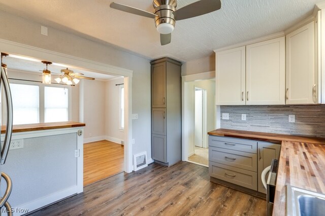 kitchen with butcher block countertops, ceiling fan, and backsplash