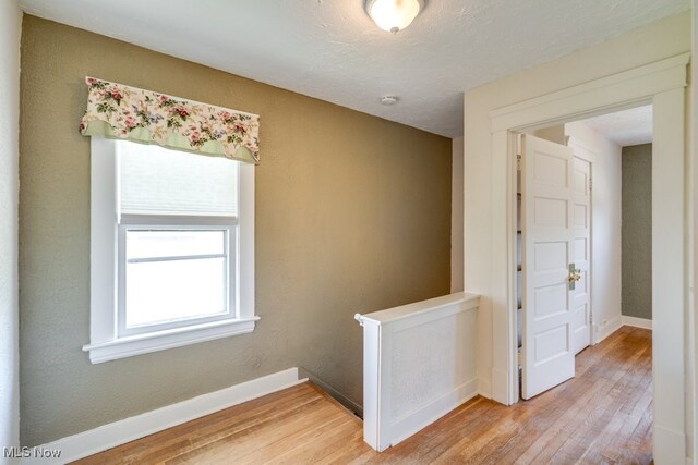 spare room featuring light wood-style floors, baseboards, and a smoke detector