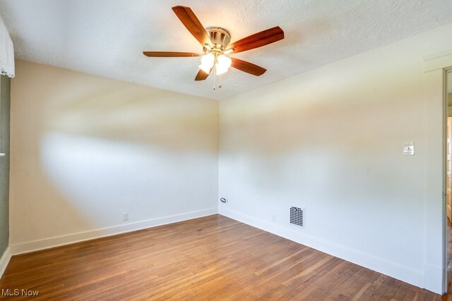 empty room featuring baseboards, ceiling fan, wood finished floors, and a textured ceiling