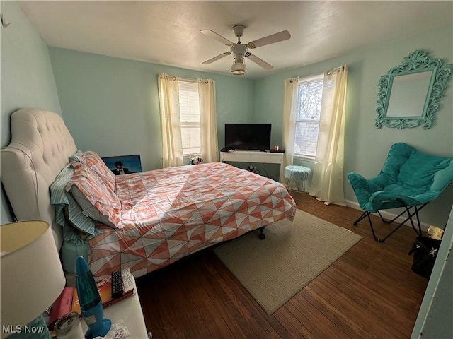 bedroom with multiple windows, wood finished floors, ceiling fan, and baseboards