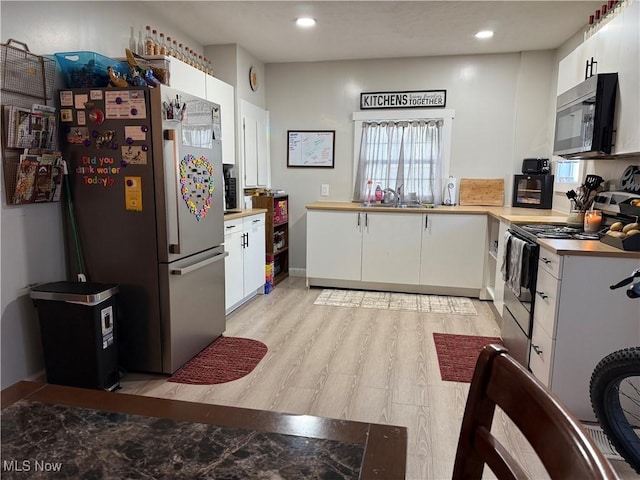 930 E Grant St, Alliance, OH 44601 - kitchen with appliances with stainless steel finishes, a sink, white cabinets, light wood finished floors, and recessed lighting