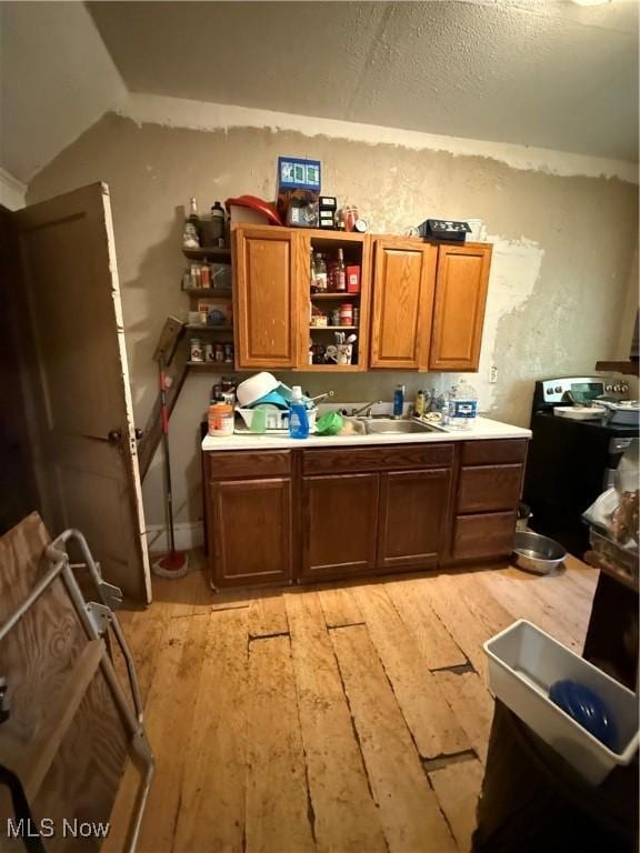 405 E Oxford St, Alliance, OH 44601 - kitchen featuring light wood-style flooring, a sink, open shelves, light countertops, and brown cabinetry
