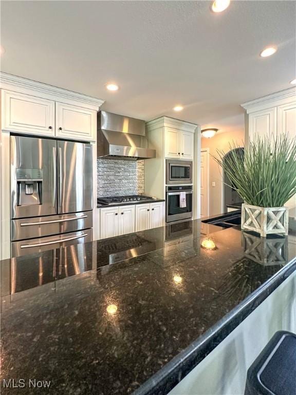 6836 Twin Oaks Ct, Canfield, OH 44406 - kitchen with appliances with stainless steel finishes, wall chimney exhaust hood, backsplash, dark stone counters, and white cabinetry