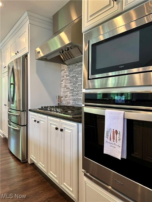 6836 Twin Oaks Ct, Canfield, OH 44406 - kitchen featuring stainless steel appliances, wall chimney range hood, dark countertops, decorative backsplash, and white cabinets