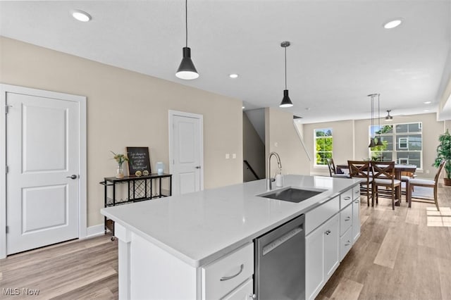 2087 Wynn Rd, Cleveland, OH 44118 - kitchen featuring a sink, stainless steel dishwasher, white cabinets, hanging light fixtures, and light wood finished floors
