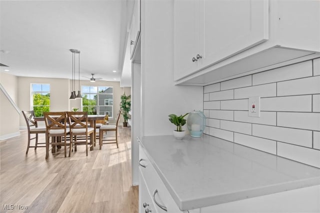 2087 Wynn Rd, Cleveland, OH 44118 - kitchen featuring backsplash, white cabinetry, light wood-style floors, ceiling fan, and light countertops