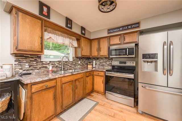 272 Cheyenne Trl, Malvern, OH 44644 - kitchen with appliances with stainless steel finishes, a sink, light wood-type flooring, tasteful backsplash, and brown cabinetry