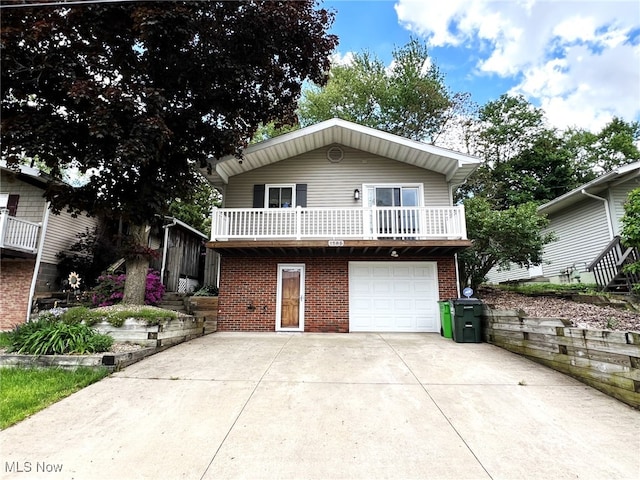 1585 Hilda St, Lakemore, OH 44250 - view of front of property featuring brick siding, concrete driveway, a garage, and a balcony