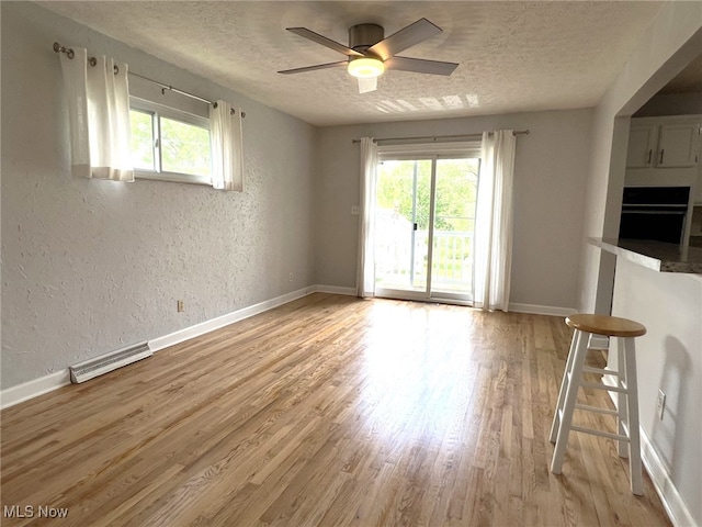 1585 Hilda St, Lakemore, OH 44250 - unfurnished living room featuring a textured ceiling, healthy amount of natural light, light wood-type flooring, a ceiling fan, and baseboards