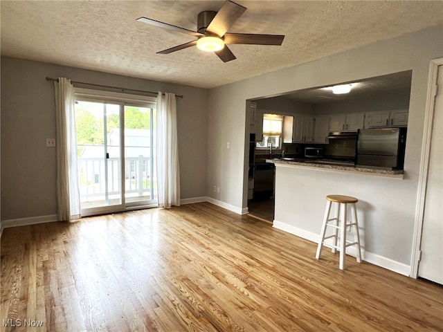 1585 Hilda St, Lakemore, OH 44250 - kitchen with appliances with stainless steel finishes, a textured ceiling, dark countertops, a peninsula, and a ceiling fan