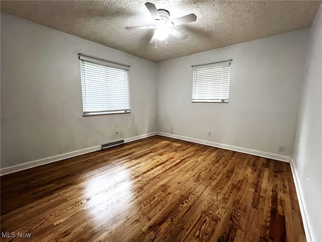 1585 Hilda St, Lakemore, OH 44250 - empty room with a textured ceiling, wood finished floors, a ceiling fan, healthy amount of natural light, and baseboards
