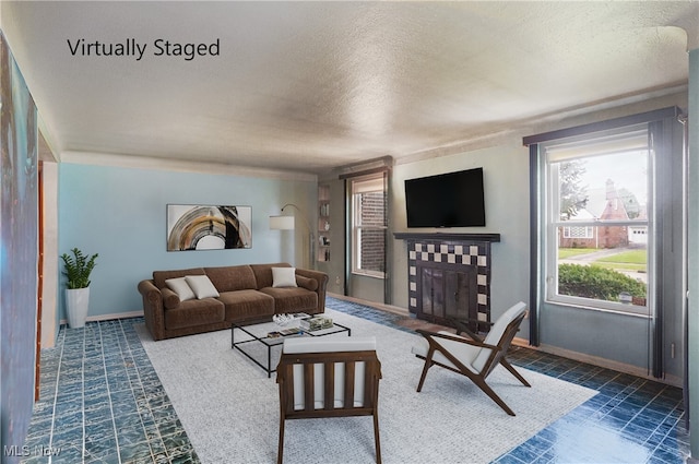living room with a fireplace, a textured ceiling, and baseboards