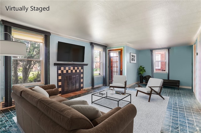 living area with a fireplace, a textured ceiling, baseboards, and plenty of natural light
