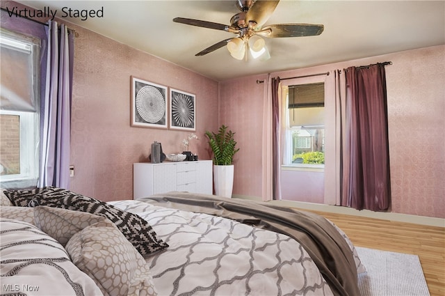 bedroom featuring wood finished floors, a ceiling fan, and baseboards