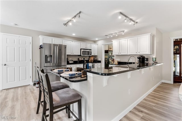114 W Cherokee Trl, Bayview, OH 44870 - kitchen with appliances with stainless steel finishes, dark countertops, a peninsula, a kitchen breakfast bar, and white cabinets