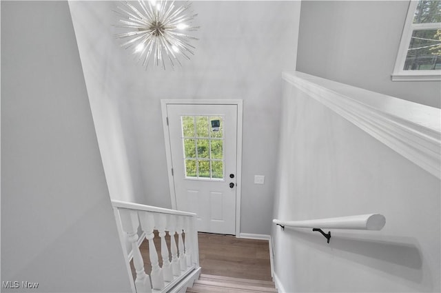 staircase featuring a chandelier, wood finished floors, and baseboards