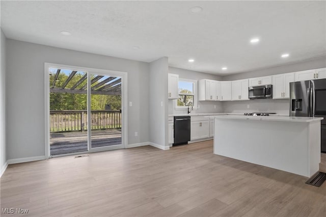 kitchen featuring stainless steel appliances, light countertops, baseboards, light wood finished floors, and recessed lighting