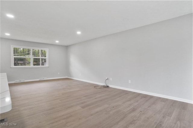 empty room featuring light wood-style flooring, recessed lighting, and baseboards