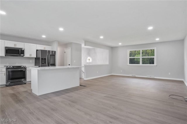 kitchen featuring appliances with stainless steel finishes, a kitchen island, light countertops, white cabinetry, and recessed lighting