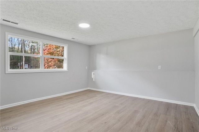 spare room featuring wood finished floors, a textured ceiling, baseboards, and recessed lighting