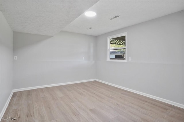empty room featuring wood finished floors, baseboards, and a textured ceiling
