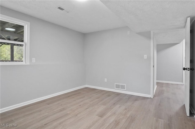 spare room with wood finished floors, baseboards, and a textured ceiling