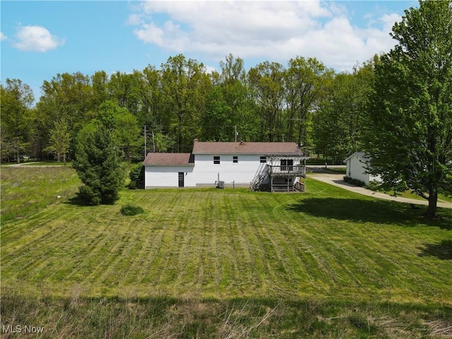 back of house with stairway, a wooden deck, and a yard