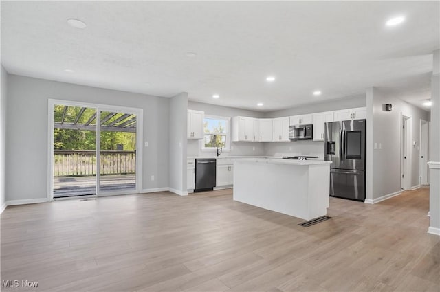 kitchen featuring stainless steel appliances, baseboards, recessed lighting, light countertops, and a kitchen island