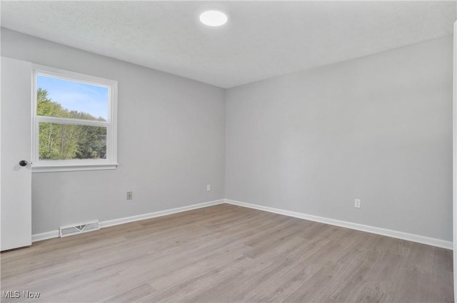 unfurnished room with light wood-style flooring and baseboards