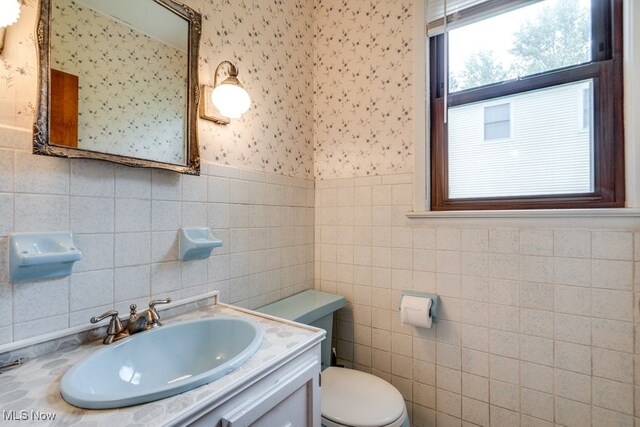 7026 S Boyden, Northfield, OH 44067 - half bath with wallpapered walls, a sink, toilet, tile walls, and wainscoting