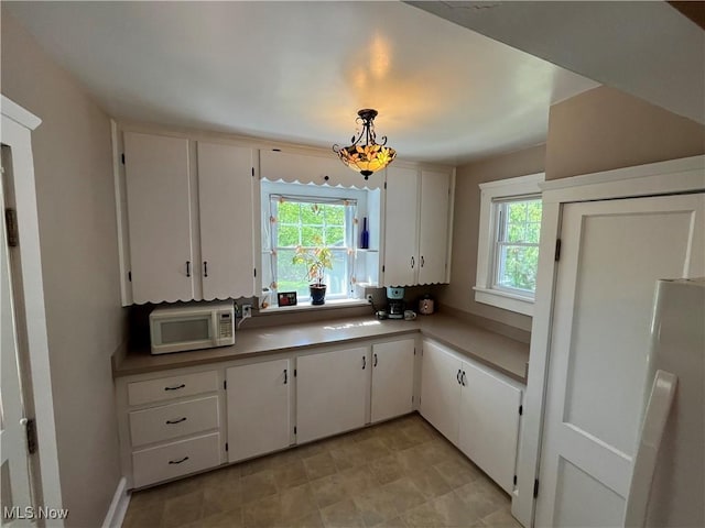 2508 Queenston Rd, Cleveland Heights, OH 44118 - kitchen with white microwave, fridge, plenty of natural light, and white cabinetry